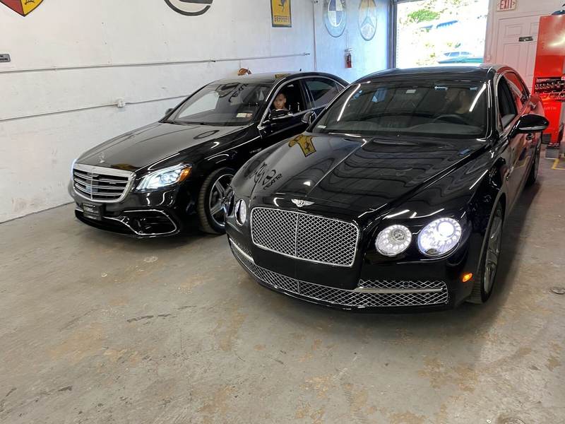 Black Bentley Flying Spur and Mercedes-Benz S-Class inside the Gold Coast Collision Center repair bay in Pompano Beach