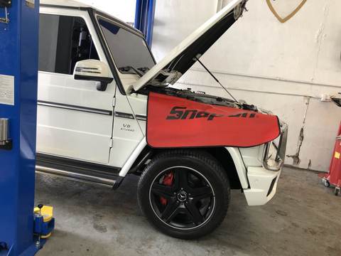 White Mercedes-AMG G63 on a lift with the hood up for mechanical repair at PorscheWorks, Pompano Beach