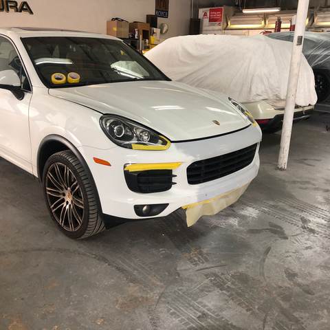 White Porsche Cayenne masked for paint in the Gold Coast Collision Center refinish bay