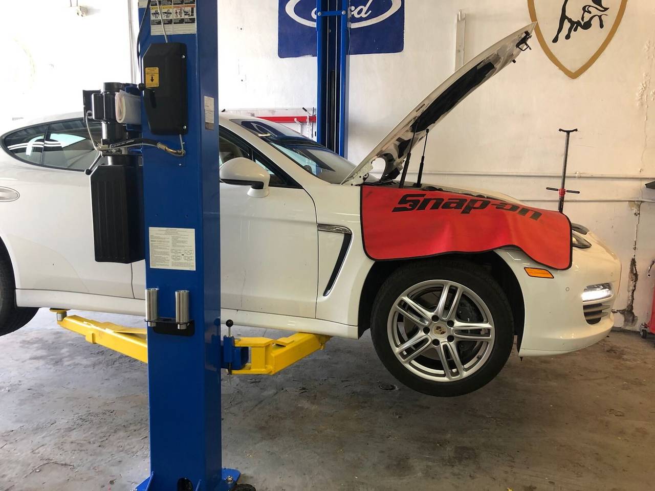 A Porsche Panamera and a Mercedes-AMG G63 on the lifts for mechanical repair at PorscheWorks in Pompano Beach